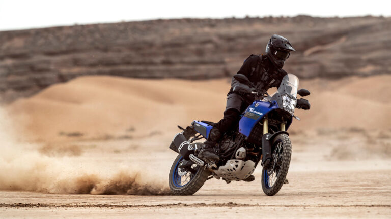 Man sieht auf dem Bild einen Motorradfahrer auf einer Yamaha Ténéré 700in blau. Er fährt durch eine Sandlandschaft und legt sich in die Kurve. Zubehör und Ersatzteile für Yamaha Ténéré 700 bei Motorradheld